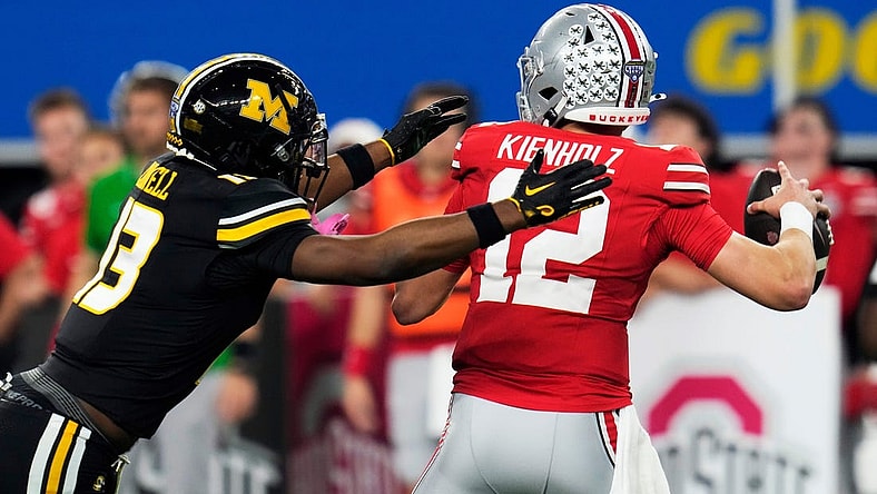 Dec 29, 2023; Arlington, Texas, USA; Ohio State Buckeyes quarterback Lincoln Kienholz (12) almost gets sacked by Missouri Tigers defensive back Daylan Carnell (13) before throwing the ball away in the second quarter during the Goodyear Cotton Bowl Classic at AT&T Stadium.