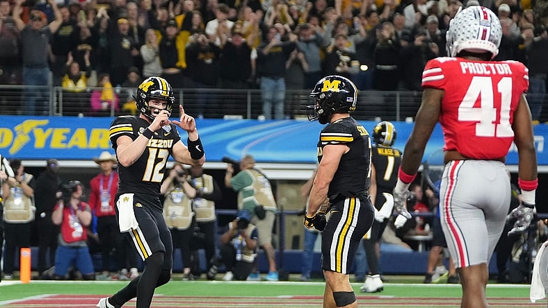 Dec 29, 2023; Arlington, Texas, USA; Missouri Tigers quarterback Brady Cook (12) pretends to take a photo of running back Cody Schrader (7) after he scored a touchdown during the third quarter of the Goodyear Cotton Bowl Classic against the Ohio State Buckeyes at AT&T Stadium. Ohio State lost 14-3.