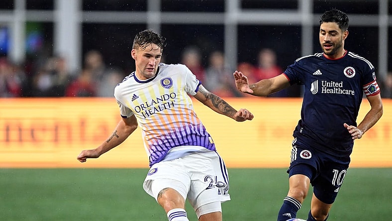 Jun 17, 2023; Foxborough, Massachusetts, USA; Orlando City defender Michael Halliday (26) passes the ball in front of New England Revolution midfielder Carles Gil (10) during the first half of a match at Gillette Stadium. Mandatory Credit: Brian Fluharty-USA TODAY Sports
