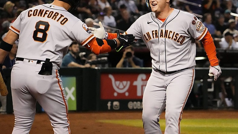 San Francisco Giants designated hitter Joc Pederson (right) reacts after hitting a home run off of Arizona Diamondbacks starting pitcher Zac Gallen (23) in the first inning at Chase Field in Phoenix on Sept. 19, 2023.