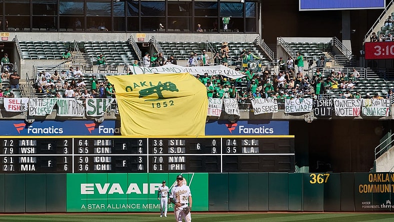 Sep 24, 2023; Oakland, California, USA; Fans in the outfield bleachers display homemade signs critical of the MLB Commissioner and Oakland Athletics ownership and Oakland Athletics infielder Zack Gelof (20) and outfielder Brent Rooker (25) stand on the field during the eighth inning against the Detroit Tigers at Oakland-Alameda County Coliseum. Mandatory Credit: Robert Edwards-USA TODAY Sports