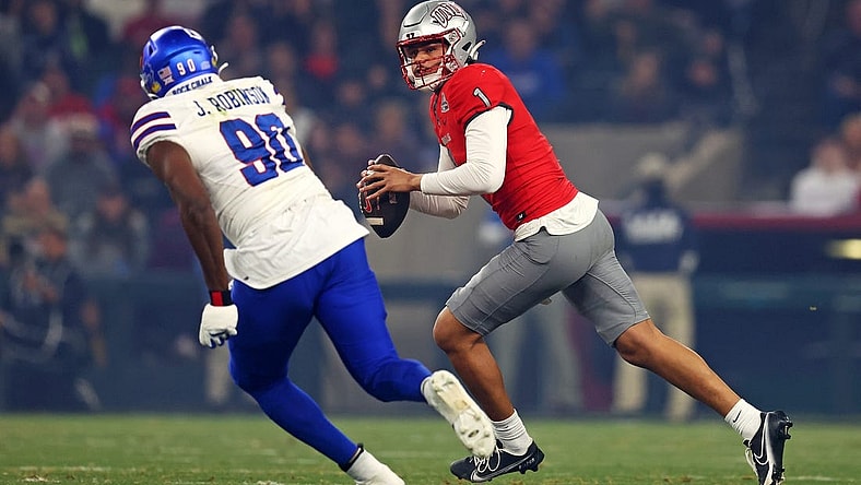 Dec 26, 2023; Phoenix, AZ, USA; UNLV Rebels quarterback Jayden Maiava (1) roles out to pass against Kansas Jayhawks defensive lineman Jereme Robinson (90) during the first quarter in the Guaranteed Rate Bowl at Chase Field. Mandatory Credit: Mark J. Rebilas-USA TODAY Sports