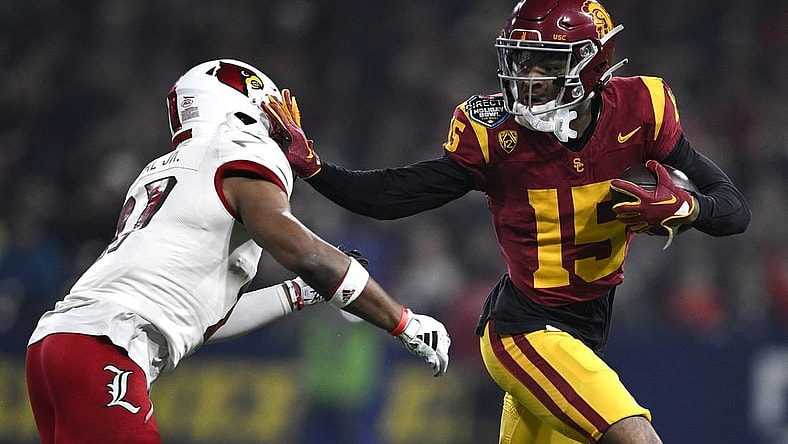 Dec 27, 2023; San Diego, CA, USA; USC Trojans wide receiver Dorian Singer (15) stiff arms Louisville Cardinals defensive back Devin Neal (27) during the first half at Petco Park. Mandatory Credit: Orlando Ramirez-USA TODAY Sports