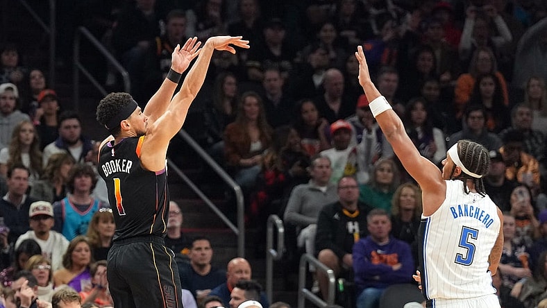Dec 31, 2023; Phoenix, Arizona, USA; Phoenix Suns guard Devin Booker (1) shoots over Orlando Magic forward Paolo Banchero (5) during the second half at Footprint Center. Mandatory Credit: Joe Camporeale-USA TODAY Sports