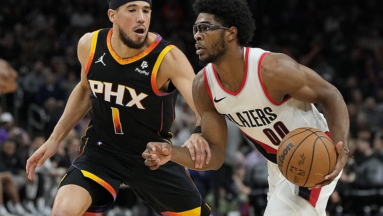 Jan 1, 2024; Phoenix, Arizona, USA; Portland Trail Blazers guard Scoot Henderson (00) drives on Phoenix Suns guard Devin Booker (1) in the second half at Footprint Center. Mandatory Credit: Rick Scuteri-USA TODAY Sports