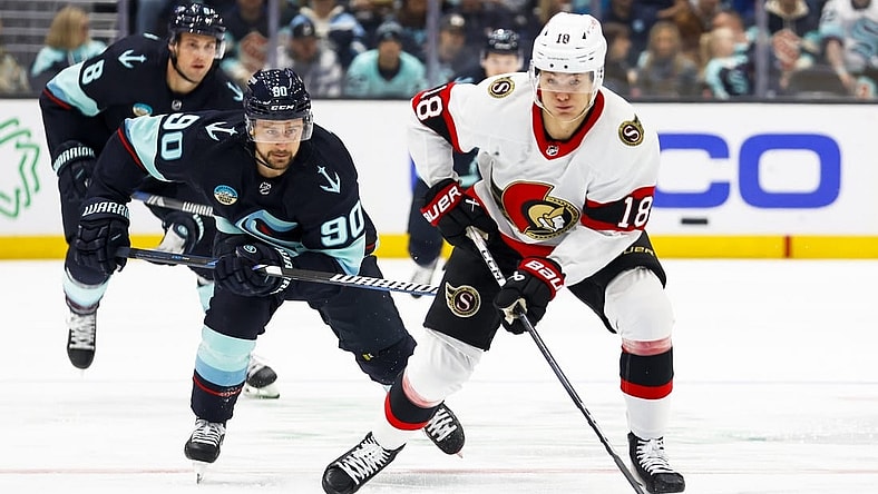 Jan 4, 2024; Seattle, Washington, USA; Ottawa Senators center Tim Stutzle (18) skates with the puck ahead of Seattle Kraken left wing Tomas Tatar (90) during the first period at Climate Pledge Arena. Mandatory Credit: Joe Nicholson-USA TODAY Sports