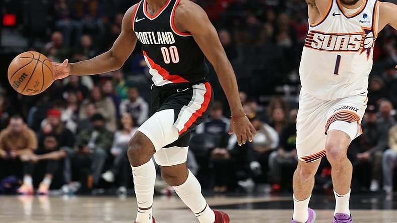 Jan 14, 2024; Portland, Oregon, USA; Portland Trail Blazers guard Scoot Henderson (00) dribbles the ball as Phoenix Suns guard Devin Booker (1) directs traffic in the first quarter at Moda Center. Mandatory Credit: Jaime Valdez-USA TODAY Sports