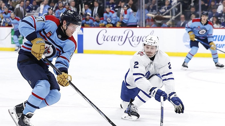 Jan 27, 2024; Winnipeg, Manitoba, CAN; Winnipeg Jets left wing Nikolaj Ehlers (27) is stick checked by Toronto Maple Leafs defenseman Simon Benoit (2) in the second period at Canada Life Centre. Mandatory Credit: James Carey Lauder-USA TODAY Sports