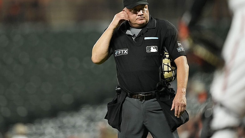 Sep 6, 2022; Baltimore, Maryland, USA; Umpire Jeff Nelson listens for the results of an instant replay review of Toronto Blue Jays shortstop Bo Bichette's (not pictured) hit against the Baltimore Orioles during the third inning at Oriole Park at Camden Yards. The review determined that Bichette hit a home run. Mandatory Credit: Brent Skeen-USA TODAY Sports