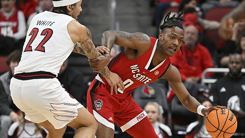 Jan 13, 2024; Louisville, Kentucky, USA;  North Carolina State Wolfpack guard DJ Horne (0) drives against Louisville Cardinals guard Tre White (22) during the first half at KFC Yum! Center. Mandatory Credit: Jamie Rhodes-USA TODAY Sports