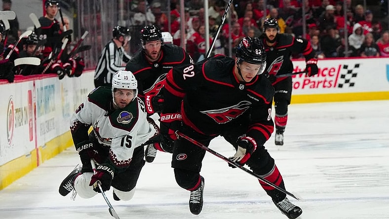 Jan 27, 2024; Raleigh, North Carolina, USA; Carolina Hurricanes center Jesperi Kotkaniemi (82) skates with the puck past Arizona Coyotes center Alexander Kerfoot (15) during the third period at PNC Arena. Mandatory Credit: James Guillory-USA TODAY Sports