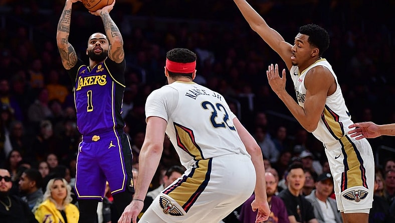 Feb 9, 2024; Los Angeles, California, USA; Los Angeles Lakers guard D'Angelo Russell (1) shoots against New Orleans Pelicans guard CJ McCollum (3) and forward Larry Nance Jr. (22) during the first half at Crypto.com Arena. Mandatory Credit: Gary A. Vasquez-USA TODAY Sports