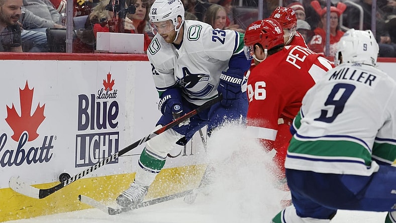 Feb 10, 2024; Detroit, Michigan, USA;  Vancouver Canucks center Elias Lindholm (23) skates with the puck defended by Detroit Red Wings defenseman Jeff Petry (46) in the third period at Little Caesars Arena. Mandatory Credit: Rick Osentoski-USA TODAY Sports