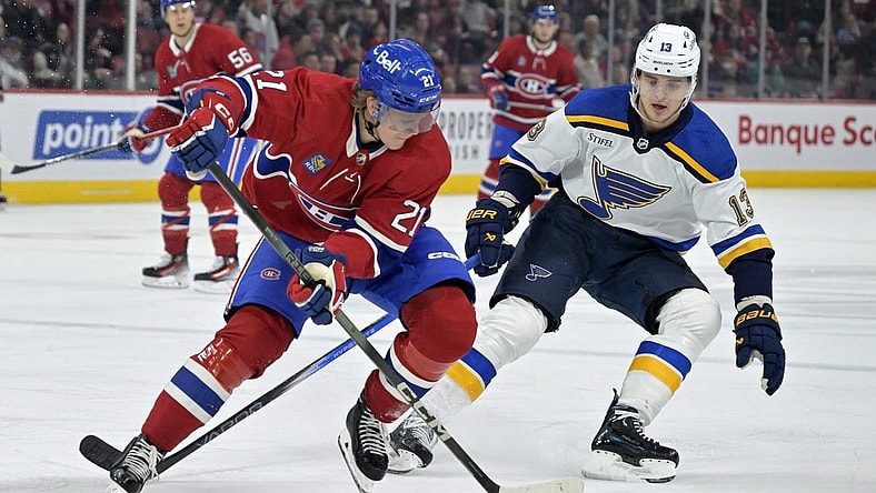 Feb 11, 2024; Montreal, Quebec, CAN; Montreal Canadiens defenseman Kaiden Guhle (21) plays the puck and St.Louis Blues forward Alexey Toropchenko (13) forechecks during the first period at the Bell Centre. Mandatory Credit: Eric Bolte-USA TODAY Sports