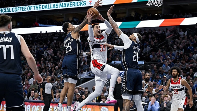 Feb 12, 2024; Dallas, Texas, USA; Washington Wizards forward Kyle Kuzma (33) drives to the basket between Dallas Mavericks forward P.J. Washington (25) and center Daniel Gafford (21) during the second quarter at the American Airlines Center. Mandatory Credit: Jerome Miron-USA TODAY Sports