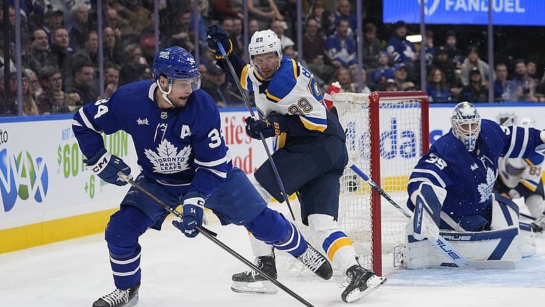 Feb 13, 2024; Toronto, Ontario, CAN; Toronto Maple Leafs forward Auston Matthews (34) goes to clear a rebound as St. Louis Blues forward Pavel Buchnevich (89) looks on during the second period Scotiabank Arena. Mandatory Credit: John E. Sokolowski-USA TODAY Sports