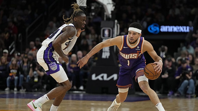 Feb 13, 2024; Phoenix, Arizona, USA; Phoenix Suns guard Devin Booker (1) drives on Sacramento Kings guard Keon Ellis (23) in the first half at Footprint Center. Mandatory Credit: Rick Scuteri-USA TODAY Sports