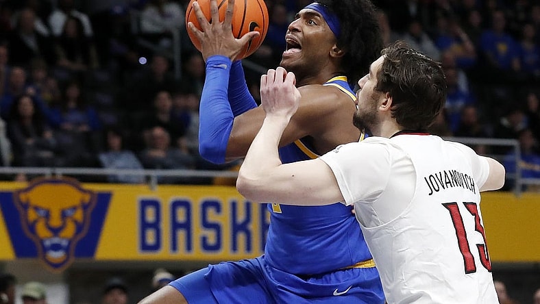 Feb 17, 2024; Pittsburgh, Pennsylvania, USA;  Pittsburgh Panthers forward Blake Hinson (left) goes to the basket against Louisville Cardinals forward Danilo Jovanovich (13) during the first half at the Petersen Events Center. Mandatory Credit: Charles LeClaire-USA TODAY Sports