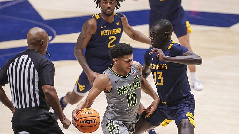 Feb 17, 2024; Morgantown, West Virginia, USA; Baylor Bears guard RayJ Dennis (10) dribbles against West Virginia Mountaineers forward Akok Akok (13) during the second half at WVU Coliseum. Mandatory Credit: Ben Queen-USA TODAY Sports