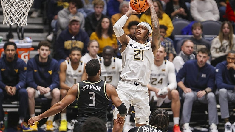 Feb 20, 2024; Morgantown, West Virginia, USA; West Virginia Mountaineers guard RaeQuan Battle (21) shoots a jumper over UCF Knights guard Darius Johnson (3) during the second half at WVU Coliseum. Mandatory Credit: Ben Queen-USA TODAY Sports
