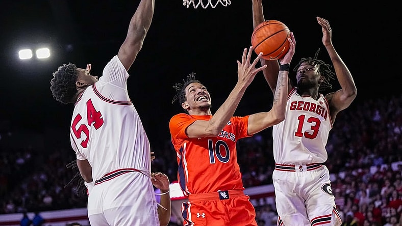 Feb 24, 2024; Athens, Georgia, USA; Auburn Tigers guard Chad Baker-Mazara (10) goes to the basket between Georgia Bulldogs center Russel Tchewa (54) and forward Dylan James (13) at Stegeman Coliseum. Mandatory Credit: Dale Zanine-USA TODAY Sports