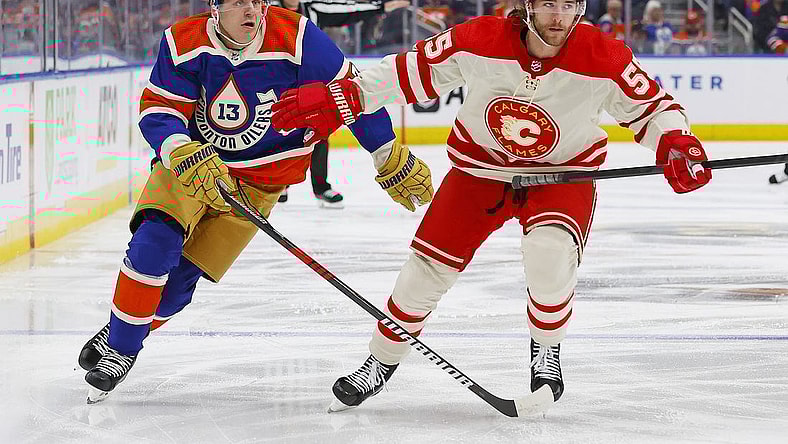 Feb 24, 2024; Edmonton, Alberta, CAN; Calgary Flames defensemen Noah Hanifin (55) and Edmonton Oilers forward Mattias Janmark (13) chase a loose puck during the first period at Rogers Place. Mandatory Credit: Perry Nelson-USA TODAY Sports
