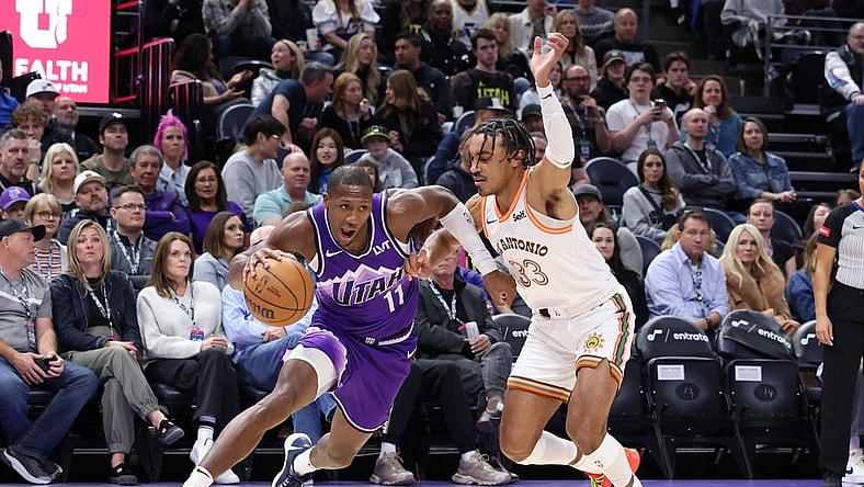 Feb 25, 2024; Salt Lake City, Utah, USA; Utah Jazz guard Kris Dunn (11) drives against San Antonio Spurs guard Tre Jones (33) during the second quarter at Delta Center. Mandatory Credit: Rob Gray-USA TODAY Sports