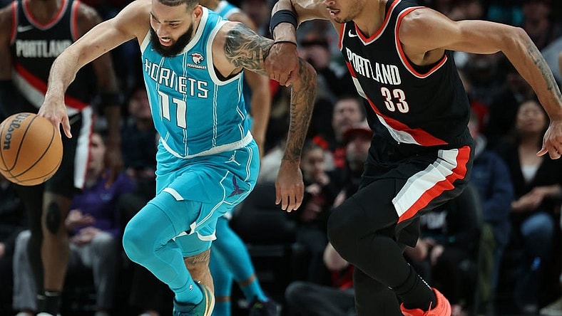 Feb 25, 2024; Portland, Oregon, USA; Charlotte Hornets forward Cody Martin (11) advances the ball past Portland Trail Blazers forward Toumani Camara (33) in the second quarter at Moda Center. Mandatory Credit: Jaime Valdez-USA TODAY Sports