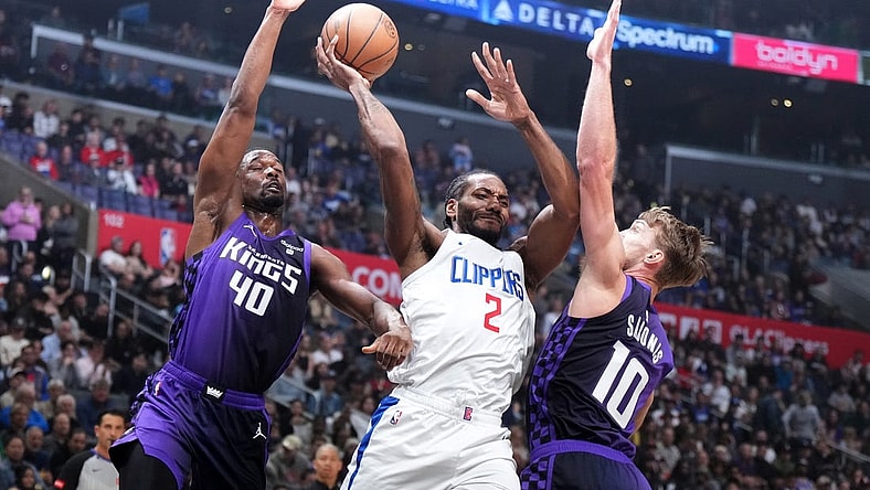 Feb 25, 2024; Los Angeles, California, USA; LA Clippers forward Kawhi Leonard (2) passes the ball against Sacramento Kings forward Harrison Barnes (40) and forward Domantas Sabonis (10) in the first half at Crypto.com Arena. Mandatory Credit: Kirby Lee-USA TODAY Sports