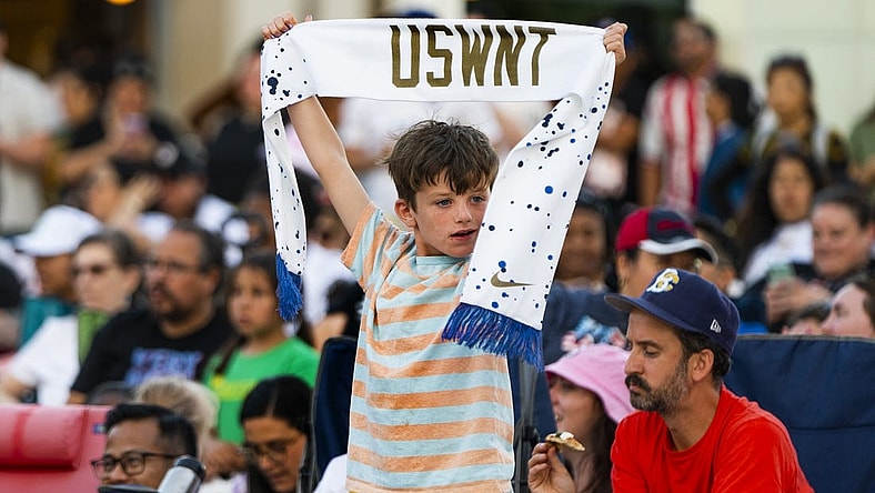 Jul 26, 2023; Los Angeles, California, USA; A young fan holds up a U.S. Women's National Team scarf in Los Angeles. Mandatory Credit: Robert Hanashiro-USA TODAY