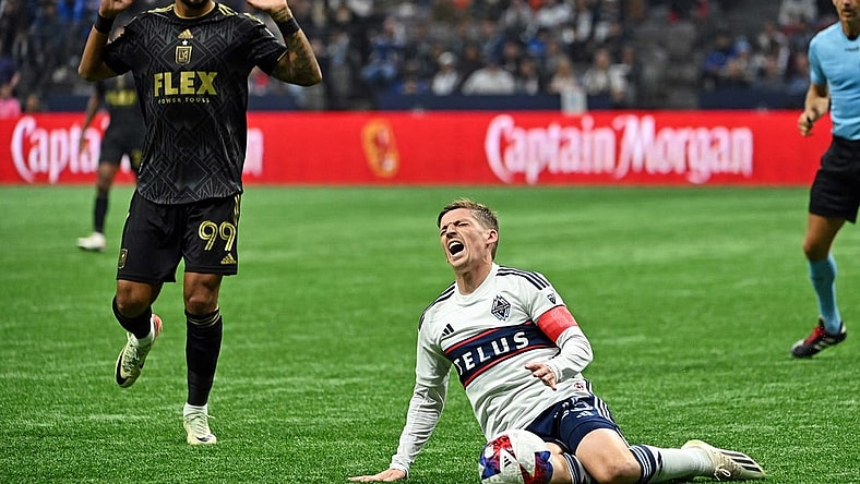 Nov 5, 2023; Vancouver, British Columbia, CAN; Vancouver Whitecaps midfielder Ryan Gauld (25) falls to the pitch against Los Angeles FC forward Denis Bouanga (99) during the second half of game two in a round one match of the 2023 MLS Cup Playoffs at BC Place. Mandatory Credit: Simon Fearn-USA TODAY Sports