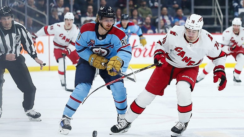 Dec 4, 2023; Winnipeg, Manitoba, CAN; Carolina Hurricanes defenseman Brady Skjei (76) and Winnipeg Jets forward Kyle Connor (81) go for the puck during the second period at Canada Life Centre. Mandatory Credit: Terrence Lee-USA TODAY Sports