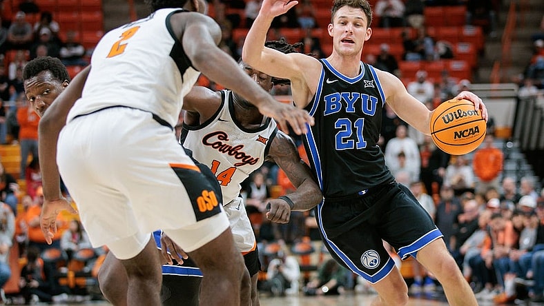 Feb 17, 2024; Stillwater, Oklahoma, USA; Brigham Young Cougars guard Trevin Knell (21) drives to the basket around Oklahoma State Cowboys guard Jamyron Keller (14) and Oklahoma State Cowboys forward Eric Dailey Jr. (2) during the second half at Gallagher-Iba Arena. Mandatory Credit: William Purnell-USA TODAY Sports