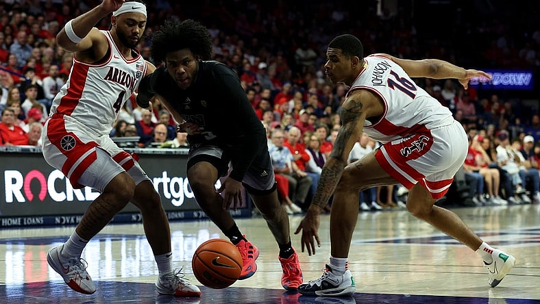 Feb 24, 2024; Tucson, Arizona, USA; Washington Huskies guard Sahvir Wheeler (5) drives to the net against Arizona Wildcats guard Kylan Boswell (4) and forward Keshad Johnson (16) during the first half at McKale Center. Mandatory Credit: Zachary BonDurant-USA TODAY Sports