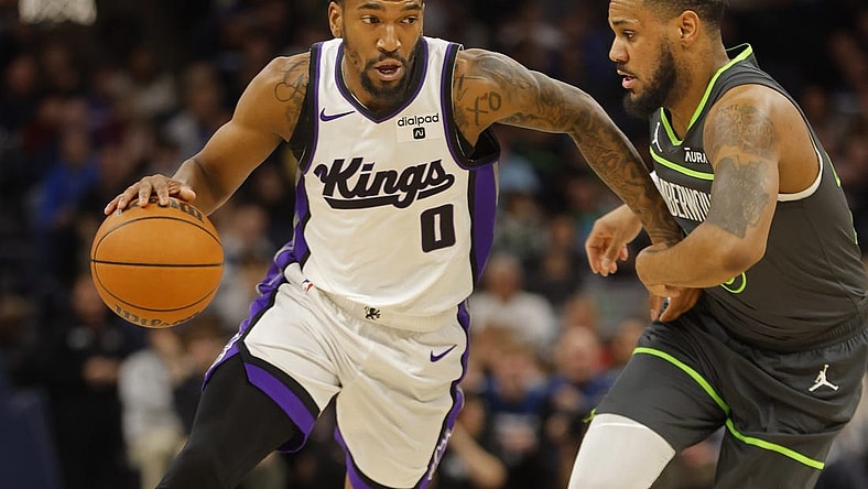 Mar 1, 2024; Minneapolis, Minnesota, USA; Sacramento Kings guard Malik Monk (0) works around Minnesota Timberwolves guard Monte Morris (23) in the first quarter at Target Center. Mandatory Credit: Bruce Kluckhohn-USA TODAY Sports