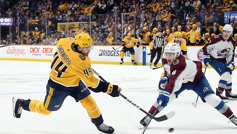 Mar 2, 2024; Nashville, Tennessee, USA; Nashville Predators left wing Kiefer Sherwood (44) shoots the puck against Colorado Avalanche defenseman Cale Makar (8) during the first period at Bridgestone Arena. Mandatory Credit: Christopher Hanewinckel-USA TODAY Sports