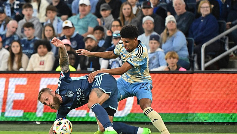 Mar 2, 2024; Kansas City, Kansas, USA; Sporting Kansas City forward Johnny Russell (7) battles Philadelphia Union defender Nathan Harriel (26) for the ball in the first half at Children's Mercy Park. Mandatory Credit: Peter Aiken-USA TODAY Sports