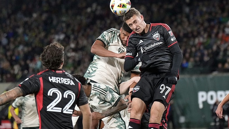 Mar 2, 2024; Portland, Oregon, USA; D.C. United defender Christopher McVey (97) heads a ball against Portland Timbers defender Zachery McGraw (18, left) during the first half at Providence Park. Mandatory Credit: Soobum Im-USA TODAY Sports