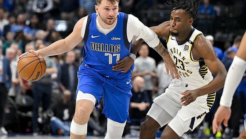 Mar 5, 2024; Dallas, Texas, USA; Dallas Mavericks guard Luka Doncic (77) looks to move the ball past Indiana Pacers forward Aaron Nesmith (23) during the first quarter at the American Airlines Center. Mandatory Credit: Jerome Miron-USA TODAY Sports