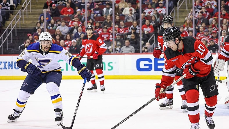 Mar 7, 2024; Newark, New Jersey, USA; New Jersey Devils right wing Alexander Holtz (10) clears the puck in front of St. Louis Blues defenseman Justin Faulk (72) during the second period at Prudential Center. Mandatory Credit: Vincent Carchietta-USA TODAY Sports