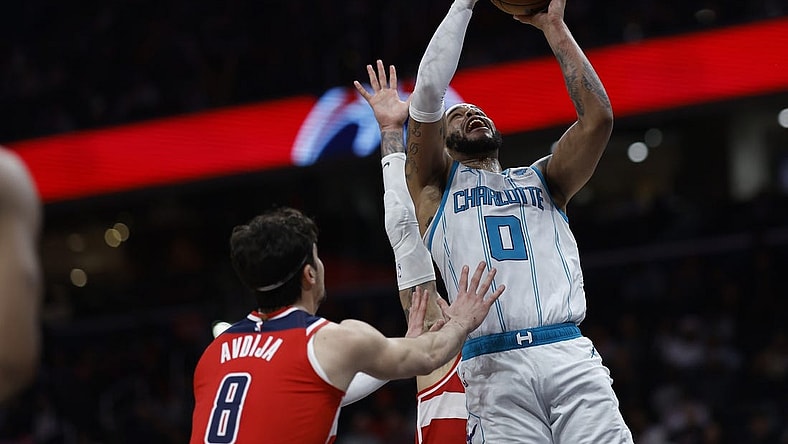 Mar 8, 2024; Washington, District of Columbia, USA; Charlotte Hornets forward Miles Bridges (0) shoots the ball as Washington Wizards forward Kyle Kuzma (33) and Wizards forward Deni Avdija (8) defend in the second half at Capital One Arena. Mandatory Credit: Geoff Burke-USA TODAY Sports