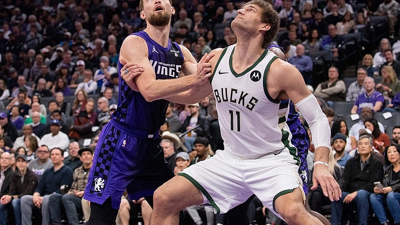 Mar 12, 2024; Sacramento, California, USA; Sacramento Kings forward Domantas Sabonis (10) and Milwaukee Bucks center Brook Lopez (11) fight for position under the basket during the second quarter at Golden 1 Center. Mandatory Credit: Ed Szczepanski-USA TODAY Sports