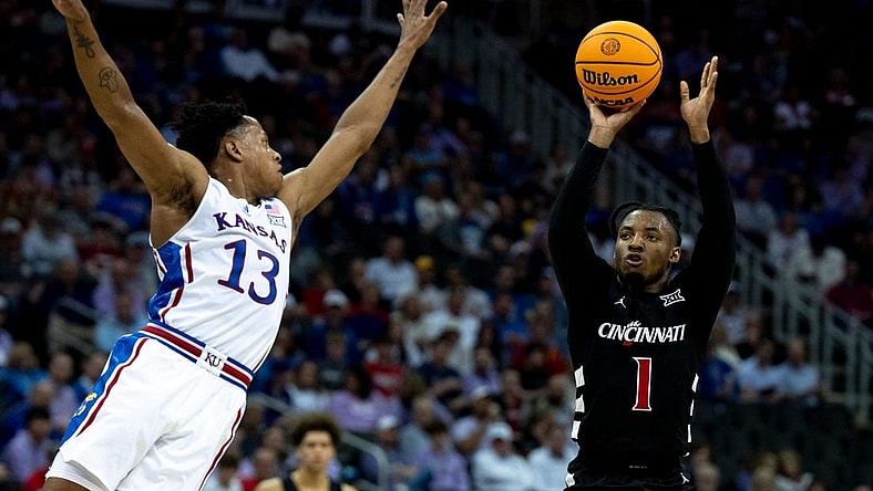 Cincinnati Bearcats guard Day Day Thomas (1) hits a 3-point basket as Kansas Jayhawks guard Elmarko Jackson (13) defends in the first half of the Big 12 Conference tournament game between Cincinnati Bearcats and Kansas Jayhawks at T-Mobile Center in Kansas City, Mo., on Wednesday, March 13, 2024.
