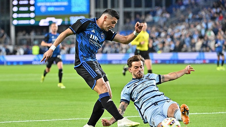 Mar 16, 2024; Kansas City, Kansas, USA; San Jose Earthquakes midfielder Cristian Espinoza (10) shoots the ball against Sporting Kansas City defender Tim Leibold (14) during the first half  at Children's Mercy Park. Mandatory Credit: Peter Aiken-USA TODAY Sports
