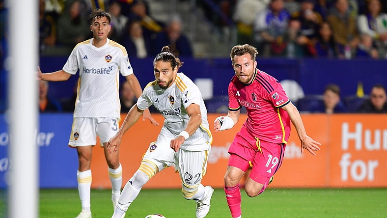 Mar 16, 2024; Carson, California, USA; LA Galaxy defender Martin Caceres (22) and St. Louis CITY SC midfielder Indiana Vassilev (19) chase down the ball during the first half at Dignity Health Sports Park. Mandatory Credit: Gary A. Vasquez-USA TODAY Sports