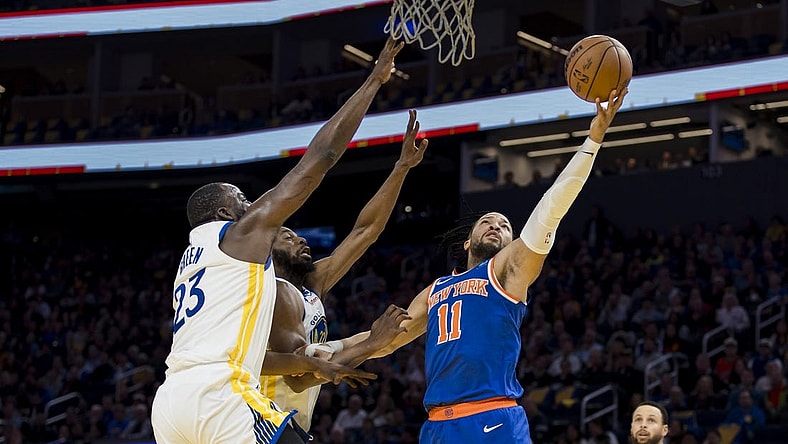 Mar 18, 2024; San Francisco, California, USA;  New York Knicks guard Jalen Brunson (11) shoots as Golden State Warriors center Draymond Green (23) and forward Andrew Wiggins (22) defend during the first half at Chase Center. Mandatory Credit: John Hefti-USA TODAY Sports