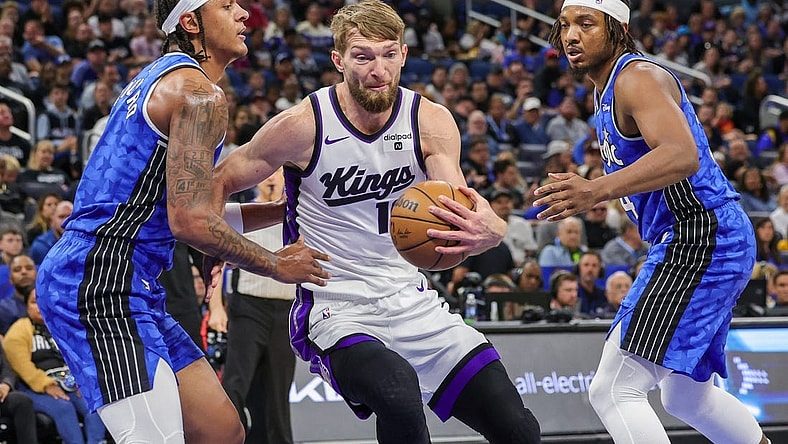 Mar 23, 2024; Orlando, Florida, USA; Sacramento Kings forward Domantas Sabonis (10) drives to the basket against Orlando Magic forward Paolo Banchero (5) and Orlando Magic center Wendell Carter Jr. (34) during the first quarter at KIA Center. Mandatory Credit: Mike Watters-USA TODAY Sports