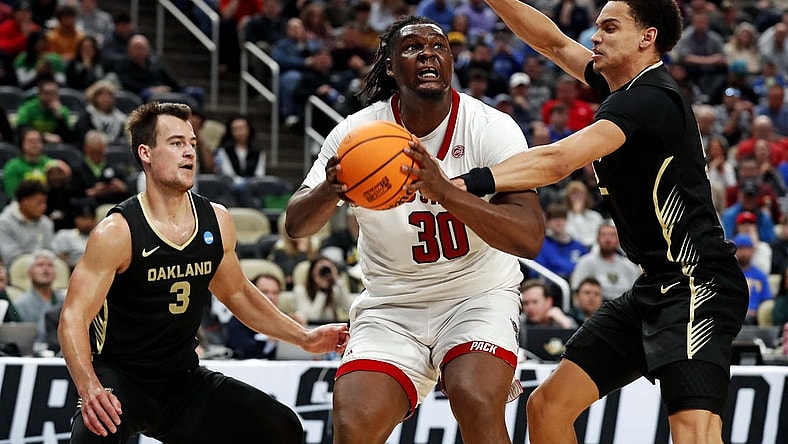 Mar 23, 2024; Pittsburgh, PA, USA; North Carolina State Wolfpack forward DJ Burns Jr. (30) drives to the basket against Oakland Golden Grizzlies forward Chris Conway (2) and guard Jack Gohlke (3) during the second half in the second round of the 2024 NCAA Tournament at PPG Paints Arena. Mandatory Credit: Charles LeClaire-USA TODAY Sports