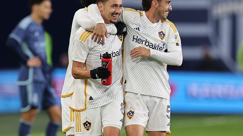 Mar 23, 2024; Kansas City, Kansas, USA; LA Galaxy midfielder Mark Delgado (8) and midfielder Gaston Brugman (5) celebrate after a Galaxy goal against Sporting Kansas City during the second half at Children's Mercy Park. Mandatory Credit: William Purnell-USA TODAY Sports