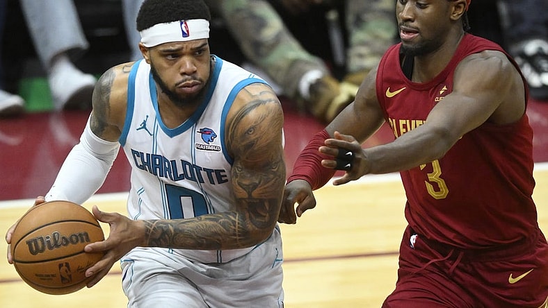 Mar 25, 2024; Cleveland, Ohio, USA; Charlotte Hornets forward Miles Bridges (0) looks to pass beside Cleveland Cavaliers guard Caris LeVert (3) in the fourth quarter at Rocket Mortgage FieldHouse. Mandatory Credit: David Richard-USA TODAY Sports